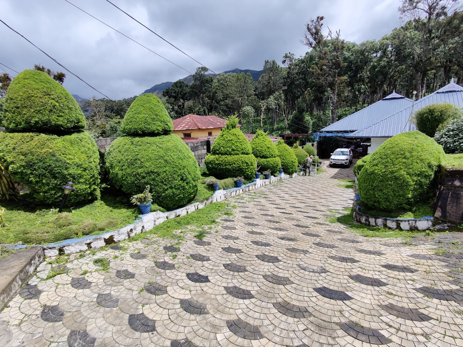 Patterned stone driveway leading up to the house, lined with trimmed hedges